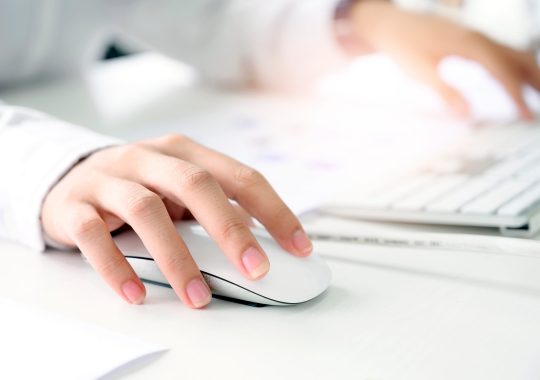 Closeup shot of female hand holding mouse and working with desktop computer.